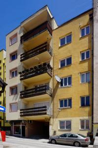 un edificio giallo con un'auto parcheggiata di fronte di Apartment View a Užice