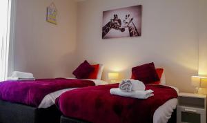 a bedroom with two beds and a picture on the wall at BellaLiving 2 Bedroom Apartment - Luton in Luton