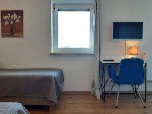 ein Schlafzimmer mit einem Schreibtisch mit einem Computer und einem blauen Stuhl in der Unterkunft Gästehaus Maria in Rettenbach am Auerberg