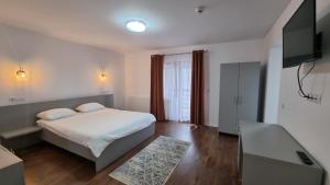 Un dormitorio con una cama con sábanas blancas y un televisor. en Pensiunea Barsan, en Vişeu de Sus