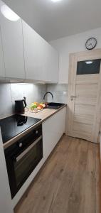 a kitchen with white cabinets and a stove and a door at Apartament Altheide in Polanica-Zdrój