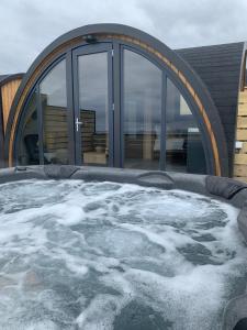 bañera de hidromasaje con nieve frente a un edificio en Orkney Lux Lodges - Hamnavoe, en Stromness