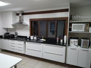 eine Küche mit weißen Schränken und einer schwarzen Arbeitsplatte in der Unterkunft Maravilhosa Casa em Angra in Angra dos Reis + 46 Fotos