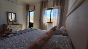 - une chambre avec un lit, un miroir et des fenêtres dans l'établissement Casa Villa D’Alvor, à Alvor