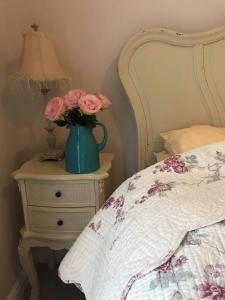 a vase with flowers on a night stand next to a bed at Lavender Cottage in Presteigne