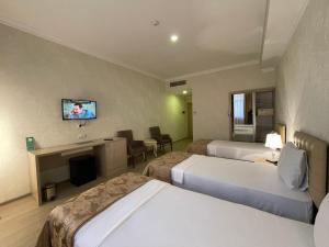 バクーにあるAmmar Grand Hotelのベッド2台、壁掛けテレビが備わるホテルルームです。