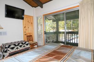 a bedroom with a bed and a balcony with a television at Sierra Park Villas #29 in Mammoth Lakes