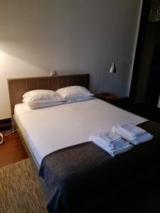 a bed with white sheets and two towels on it at Rosa Biscoito Suites in Luso