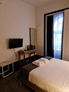 ルーゾにあるRosa Biscoito Suitesのベッド、デスク、テレビが備わるホテルルームです。