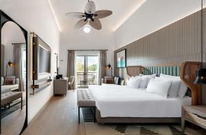 a bedroom with a large white bed with a ceiling fan at Radisson Collection Hotel, Bodrum in Akyarlar