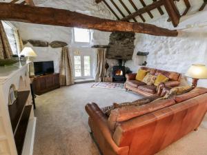 a living room with a leather couch and a fireplace at Ty Cerrig in Llanbedr