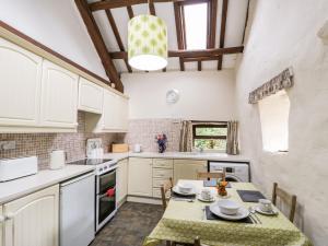 a kitchen with white cabinets and a table with chairs at Ty Cerrig in Llanbedr