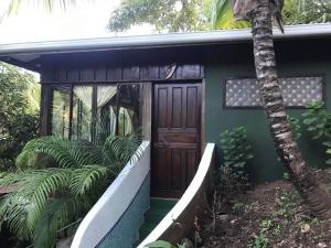 a green house with a door and a palm tree at FLOR DE PARAISO BUNGALOWS in Montezuma