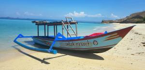 a small boat sitting on a beach next to the ocean at Ombak Resort at Ekas , a luxury surf and kite destination, Close to Inside Ekas beach in Ekas