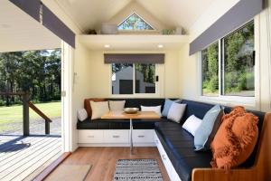 a living room in a tiny house with a couch and a table at Pindari Tiny Home Kangaroo Valley in West Cambewarra