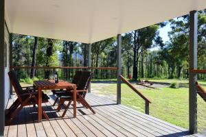eine Holzterrasse mit einem Tisch und 2 Stühlen in der Unterkunft Pindari Tiny Home Kangaroo Valley in West Cambewarra
