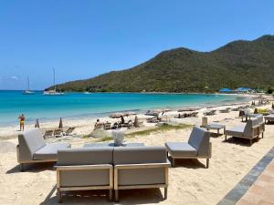 a beach with chairs and umbrellas and the ocean at Le Domaine Anse Marcel Beach Resort in Anse Marcel 