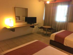 ein Hotelzimmer mit 2 Betten und einem Schreibtisch mit einem Spiegel in der Unterkunft Hotel Villablanca in Tehuacán