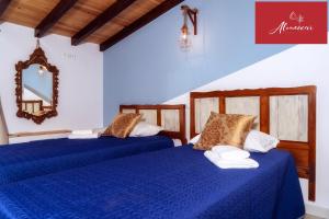 two beds in a room with blue sheets and a mirror at Guest House Almeixar in Almancil