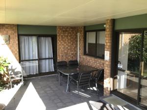 a patio with a table and chairs and windows at SilverSands in Waihi Beach