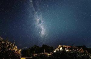 a starry night with the milky way above a house at Rock Retreat B&B farmstay in Waitomo Caves