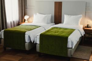 two beds with green sheets in a hotel room at Hotel Amurskiy in Irkutsk