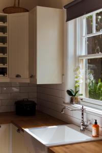 cocina con fregadero blanco y ventana en Illalangi Boutique Cottage, en Blackheath