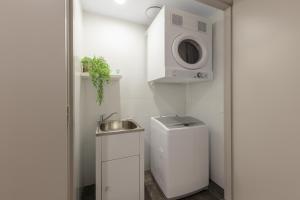 a kitchen with a white refrigerator and a white sink at Meriton Suites North Ryde in Sydney
