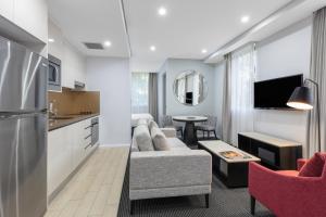 a living room filled with furniture and a tv at Meriton Suites North Ryde in Sydney