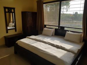 a bedroom with a large bed with a large window at Status Homeaway Service Apartments in Nashik