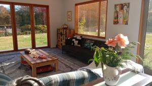 uma sala de estar com um sofá e uma mesa em Rose & Stream Retreat em Waikuku