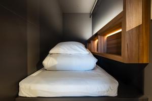 uma pequena cama num pequeno quarto com uma almofada em UNPLAN Fukuoka em Fukuoka