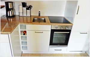 a kitchen with white cabinets and a sink at 4-ZIMMER-FERIENWOHNUNG DEICHWIESE -Westerland-Sylt - Garten - Terrasse - 3 Schlafzimmer - 2 - 5 Pers in Westerland (Sylt)