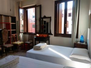 um quarto com uma cama branca e 2 janelas em Cà Widmann em Veneza