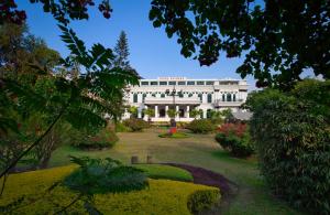 ein großes weißes Gebäude mit einem Garten davor in der Unterkunft Hotel Shanker-Palatial Heritage Kathmandu in Kathmandu