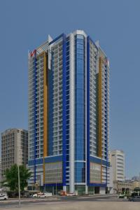 a large white building with a blue sky at Swiss-Belsuites Admiral Juffair in Manama