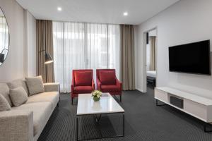 a living room with a couch and two red chairs at Meriton Suites North Ryde in Sydney