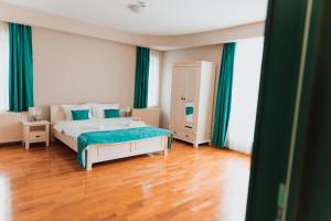 una camera da letto con letto, tende verdi e pavimenti in legno di Pensiunea Green Villa a Sibiu