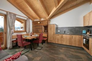 - une cuisine avec des placards en bois, une table et des chaises dans l'établissement Ferienhaus Rohrmoos Maria Alm, à Maria Alm
