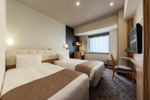 a hotel room with two beds and a television at Hotel Villa Fontaine Grand Tokyo-Shiodome in Tokyo