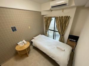 een hotelkamer met een bed en een tafel met een telefoon bij Exsaison Shirokita 412 in Osaka