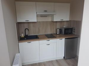 a kitchen with white cabinets and a sink and a microwave at Dworek pod Lwami in Lewin Brzeski