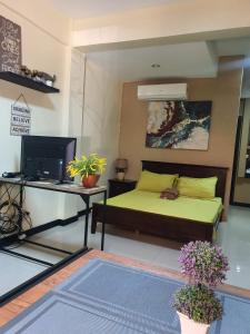 a bedroom with a bed and a desk and a television at Carlo'S Place in Dumaguete