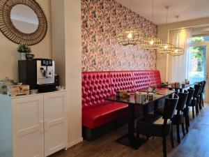 uma sala de jantar com um banco vermelho e uma mesa em Boutique Hotel De Raetskamer em Noordwijkerhout