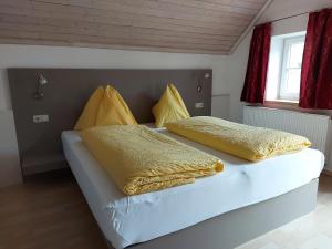 1 Schlafzimmer mit 2 Betten und gelben Kissen in der Unterkunft K3 Ferienhaus in Strobl