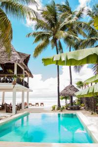 uma piscina ao lado de uma praia com palmeiras em Maisha Matamu Beach Hotel Paje em Paje
