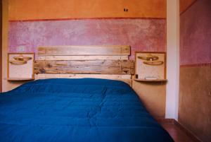 a bedroom with a blue bed and a wooden headboard at B&B Terra e Paglia in SantʼAnna