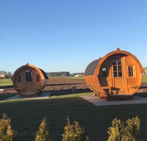 two circular wooden houses sitting in a field at Holz Fässla in Wolframs-Eschenbach