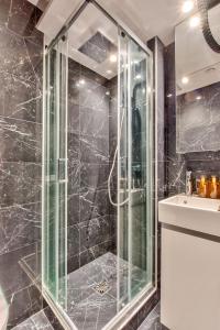 a bathroom with a glass shower and a sink at 104 - Urban Opera Lafayette in Paris