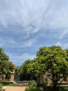 a tree in front of a building with a cloudy sky at The Postcard Gir Wildlife Sanctuary in Sasan Gir